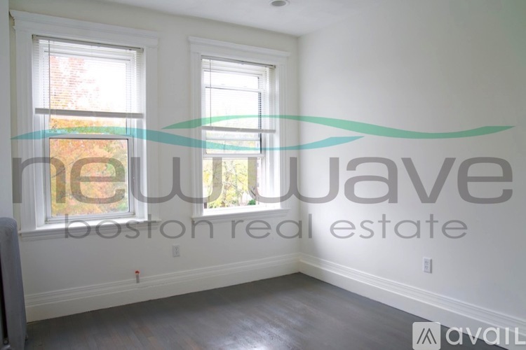 A room with a window and a wall with a logo for New Wave Boston Real Estate.