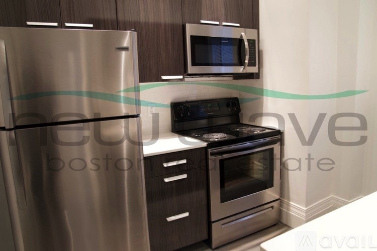 A modern kitchen with a stainless steel refrigerator, microwave, and oven.