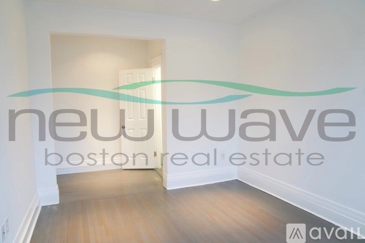A room with a wooden floor and a wall with the text "new wave boston real estate".