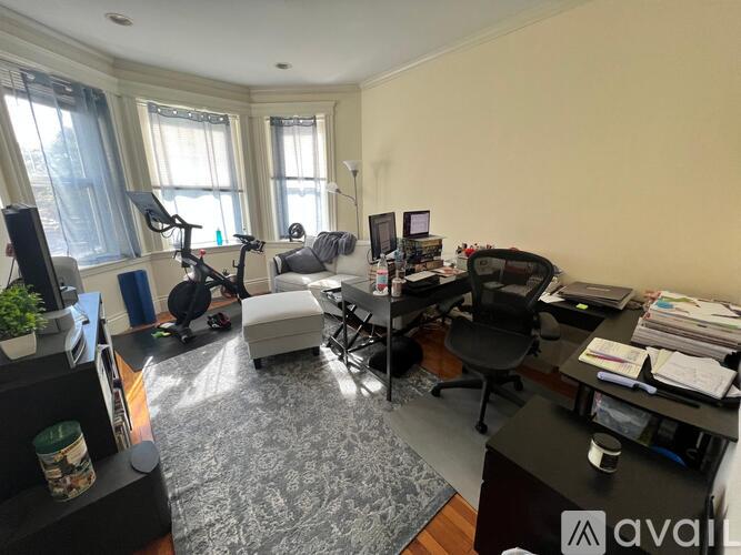A home office with a desk, chair, and exercise equipment.