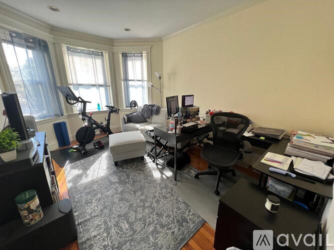 A home office with a desk, chair, and exercise equipment.