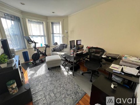 A home office with a desk, chair, and exercise equipment.