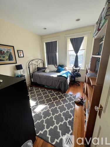 A bedroom with a bed, a chair, and a rug.