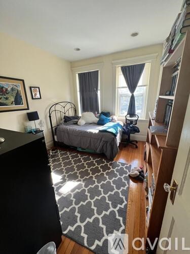 A bedroom with a bed, a chair, and a rug.