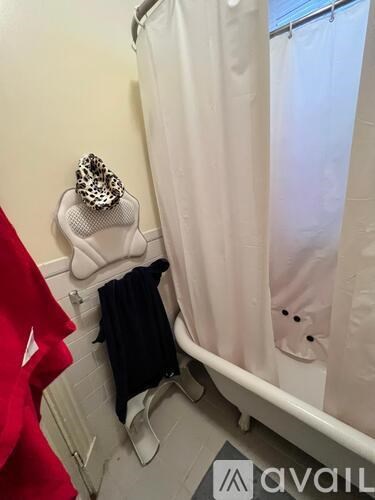 A bathroom with a white shower curtain and a red jacket hanging on the wall.