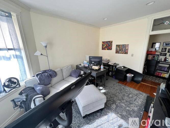 A living room with a white couch and a grey ottoman.