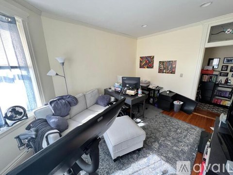 A living room with a white couch and a grey ottoman.