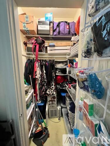 A small closet is packed with clothes and bags.