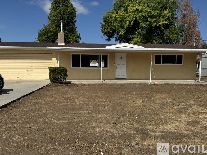 A house with a white door and windows is surrounded by a brown dirt area.