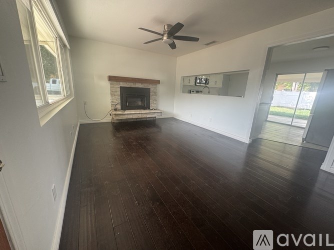 A spacious room with a fireplace and a ceiling fan.