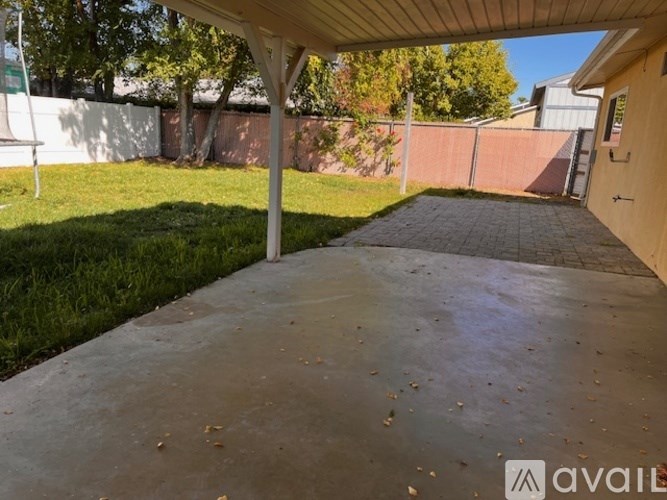 A patio area with a concrete floor and a white pergola.
