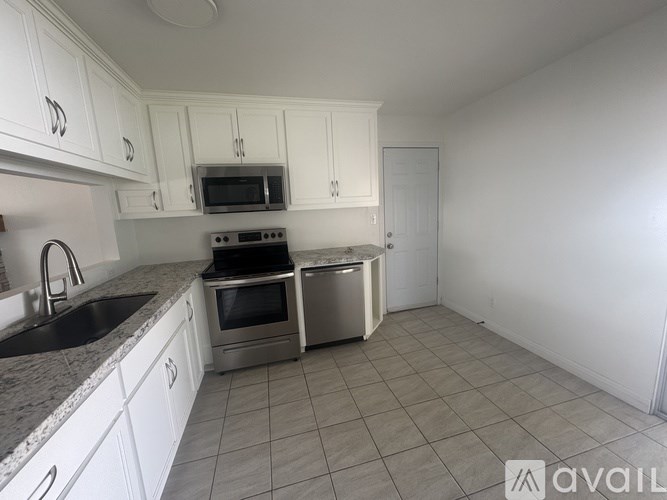 A kitchen with white cabinets and a granite countertop.