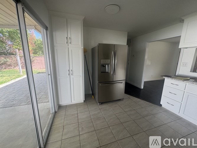 A kitchen with white cabinets and a tiled floor.