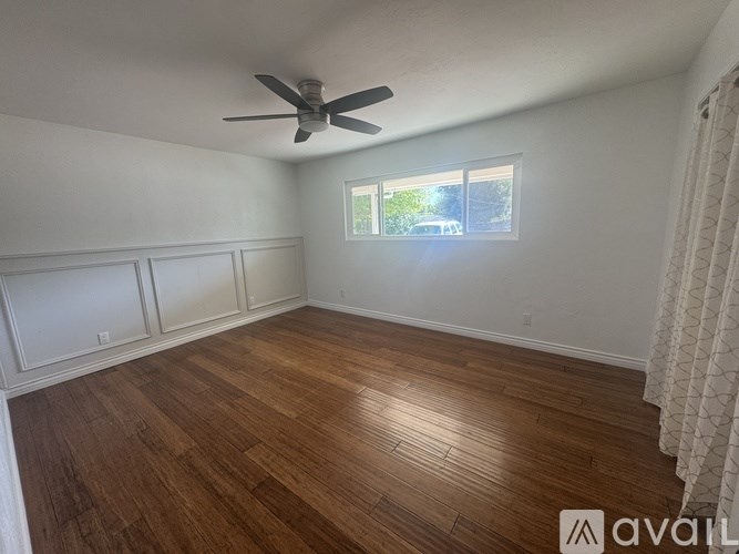 A room with wooden flooring and a ceiling fan.