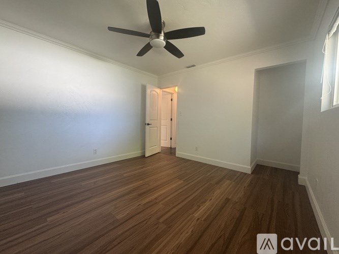 A room with a ceiling fan and wooden flooring.
