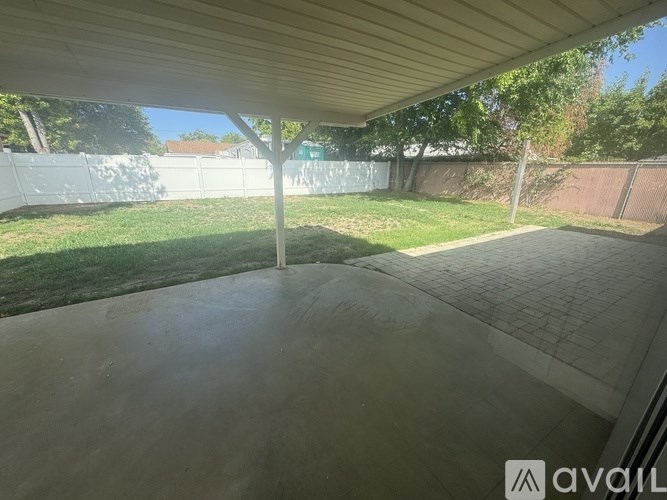 A patio with a white fence and green grass in the background.