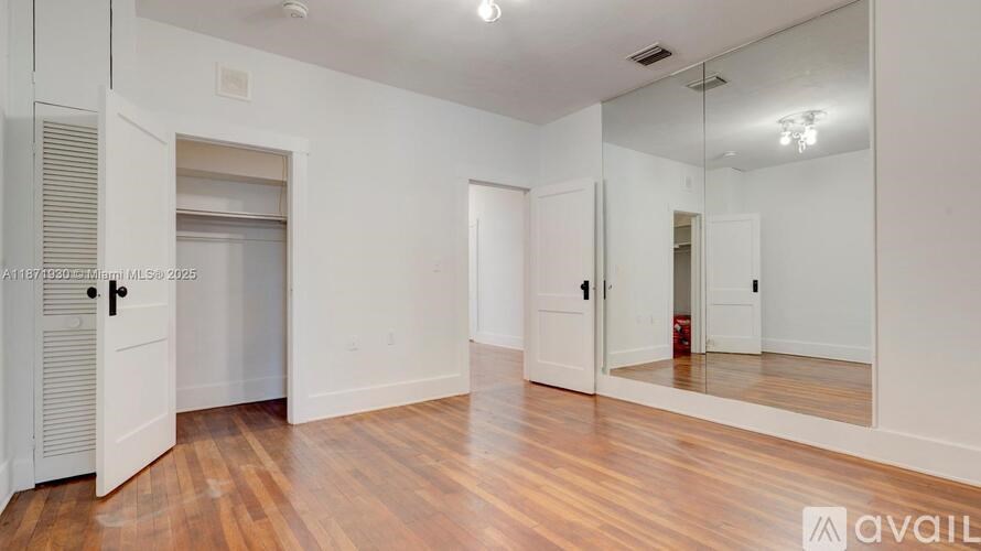 A spacious room with wooden floors and white walls.