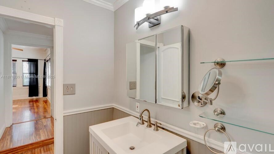 A bathroom with a sink, mirror, and light fixture.