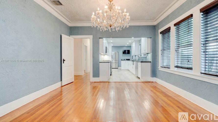 A spacious room with wooden floors and a chandelier.