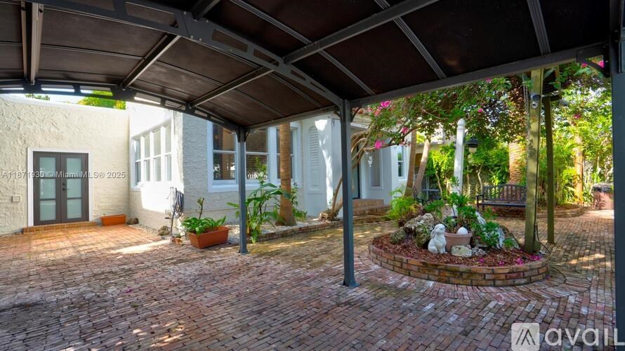 A patio area with a brick floor and a garden.