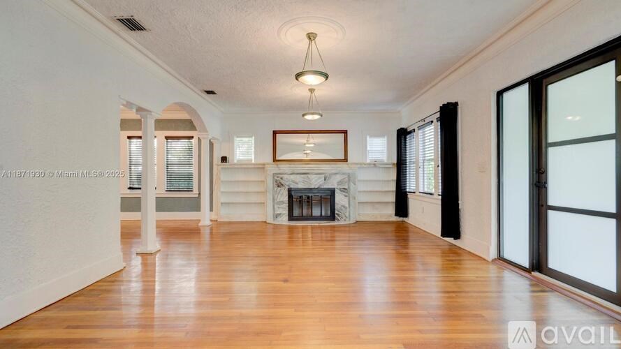 A spacious room with wooden floors and a large window on the right side.