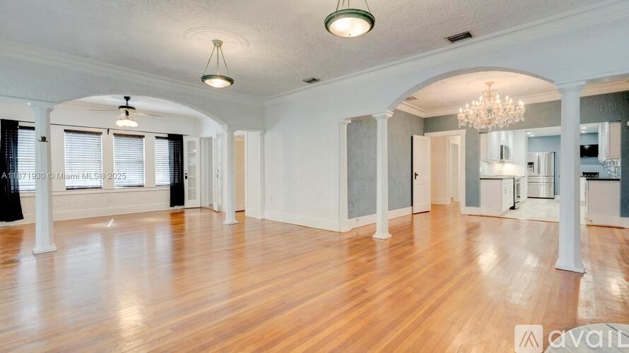 A spacious room with wooden floors and arched doorways.