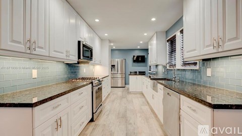 A kitchen with white cabinets and a black countertop.