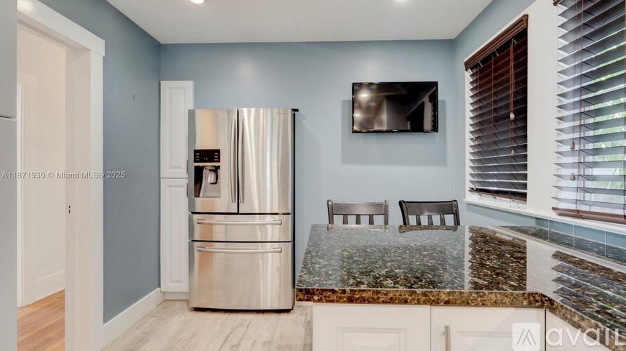 A kitchen with a stainless steel refrigerator and a television mounted on the wall.