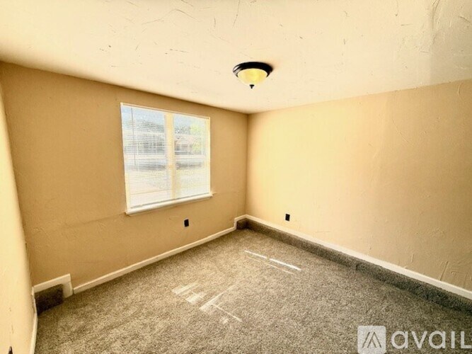 A room with a carpeted floor and a window with blinds.