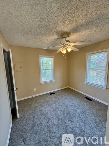 A room with a ceiling fan and two windows.