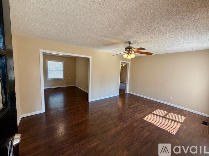 A room with a ceiling fan and wooden flooring.