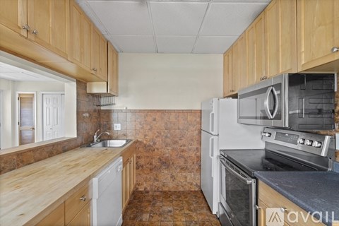A kitchen with wooden cabinets and brown tiled walls.