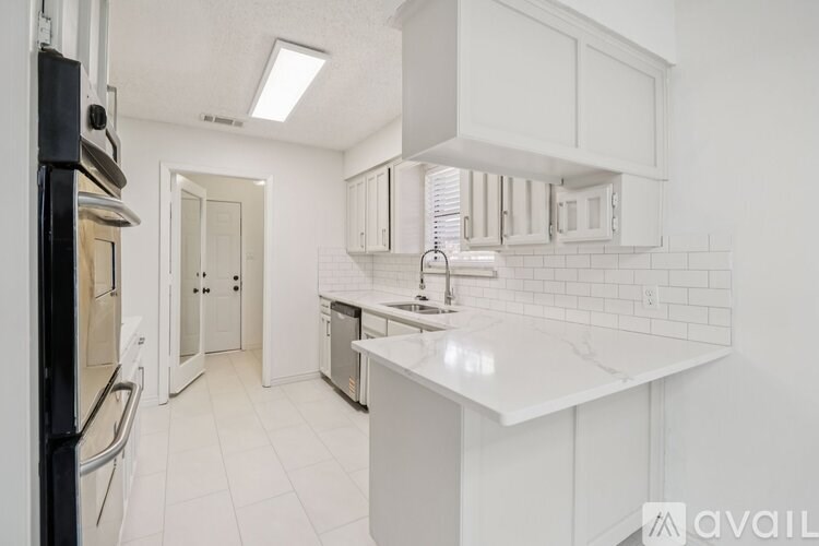 A white kitchen with a refrigerator, sink, and cabinets.