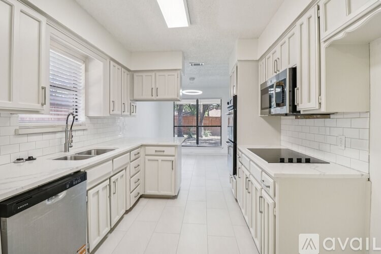 A kitchen with white cabinets and appliances.