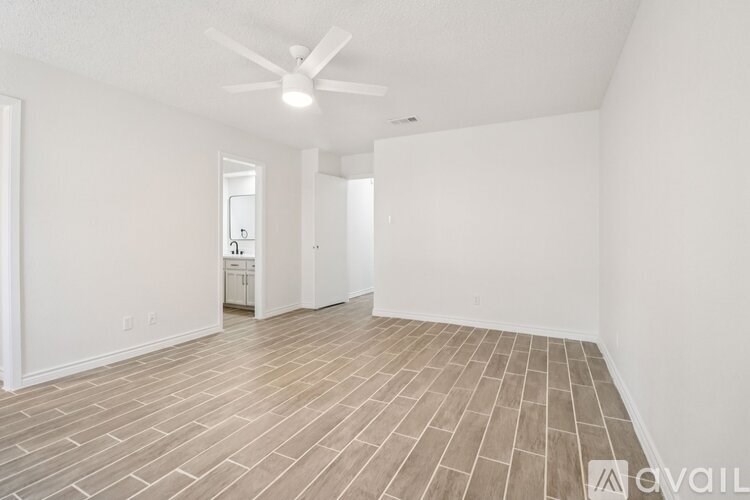 A spacious room with a ceiling fan and wooden flooring.