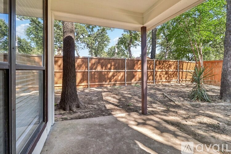 A patio area with a tree and a fence in the background.