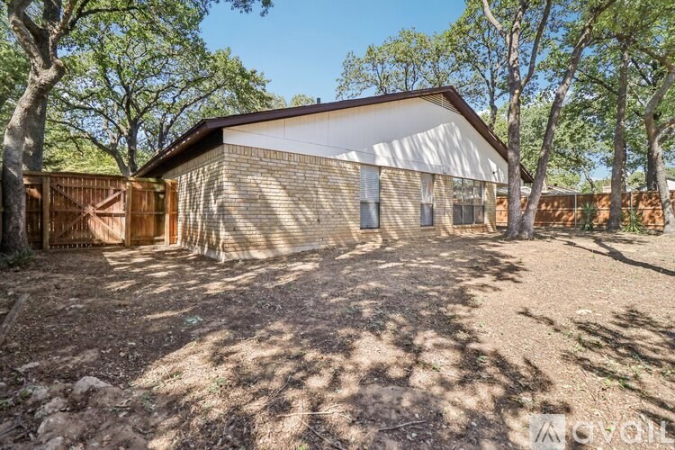 A house with a brown roof and a white garage door is surrounded by trees.