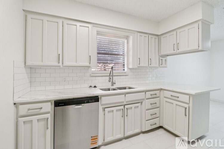 A kitchen with white cabinets and a black dishwasher.