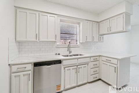A kitchen with white cabinets and a black dishwasher.