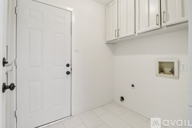 A white door is open to a room with white walls and a white floor.