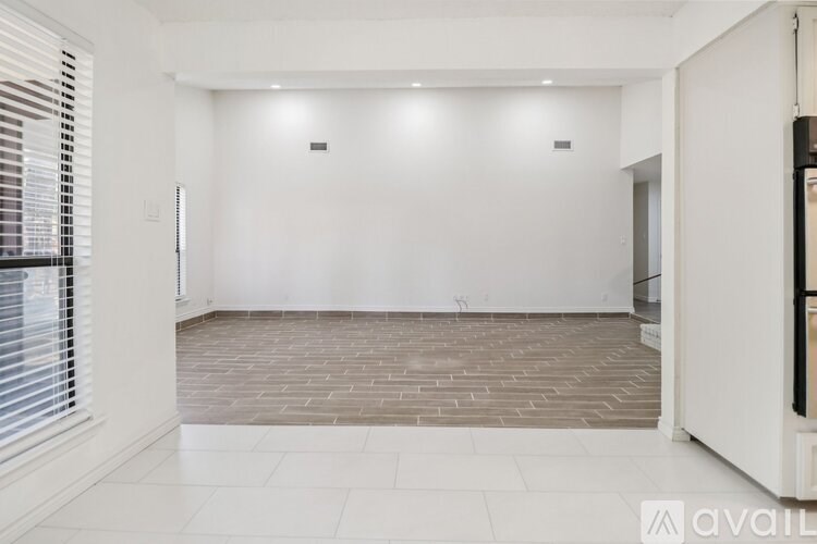 A spacious room with a tiled floor and a white wall.