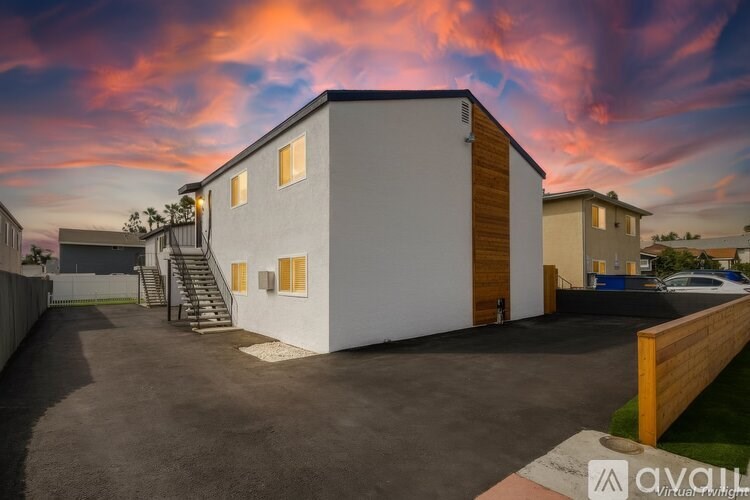 A modern house with a wooden fence and a driveway in front.