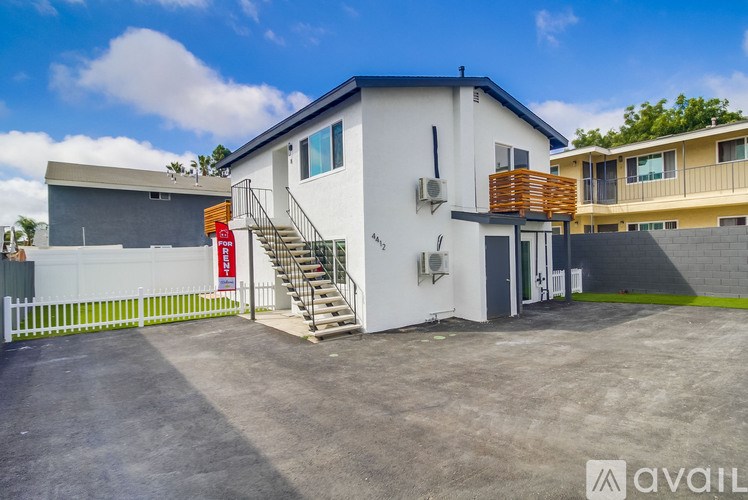 A white building with a red sign on the gate.