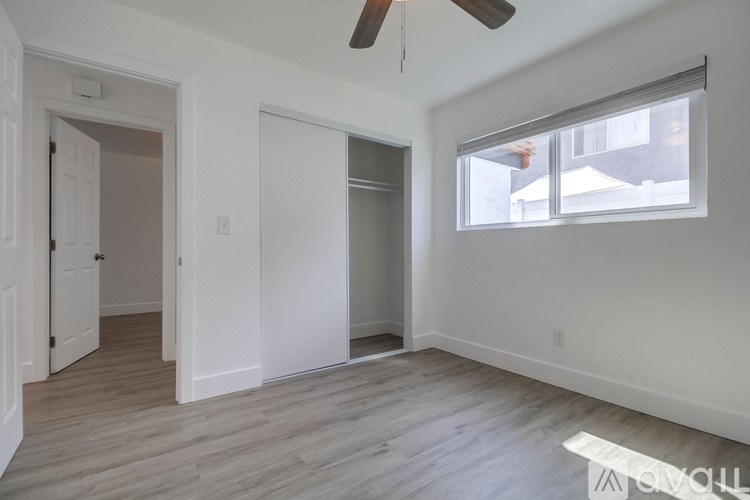 A room with a ceiling fan and a window with blinds.