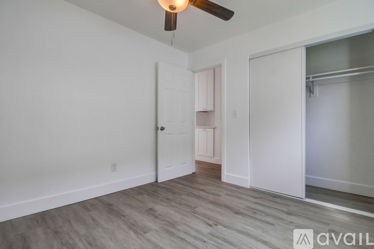 A room with a ceiling fan and a door leading to another room.