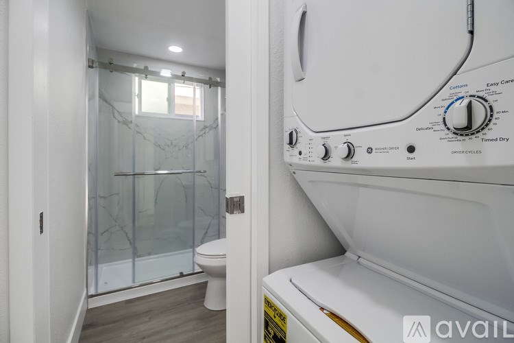A white dryer is next to a toilet in a small bathroom.