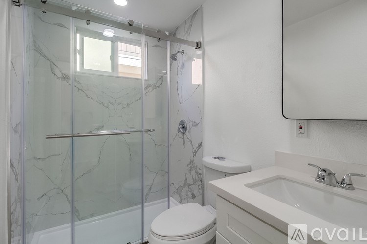 A bathroom with a marble patterned shower and toilet.