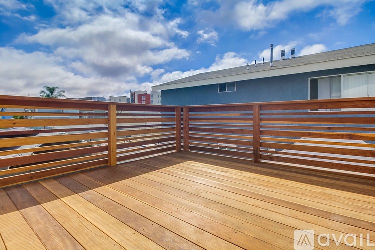 A wooden deck with a railing and a building in the background.