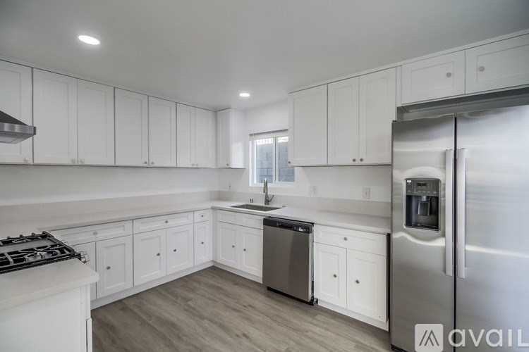A modern kitchen with white cabinets and stainless steel appliances.