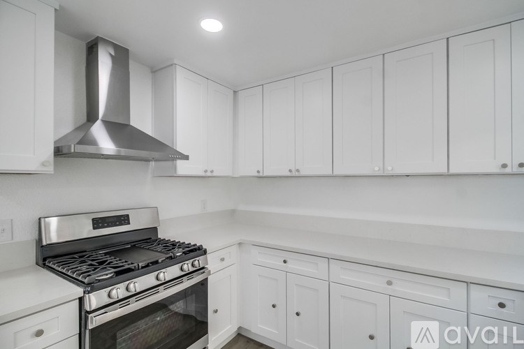 A modern kitchen with white cabinets and a stainless steel range hood.